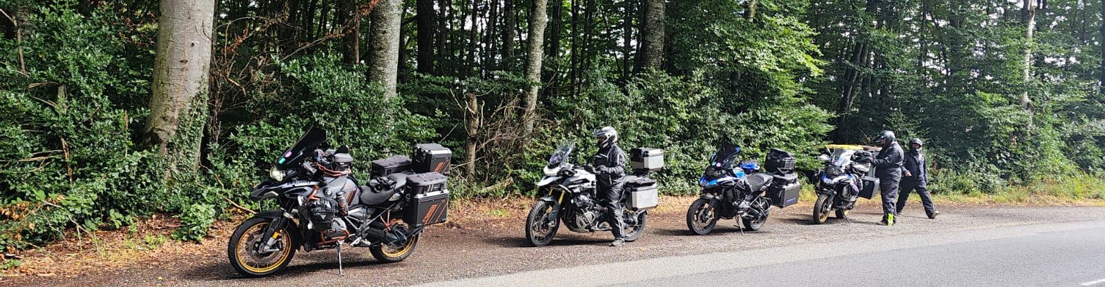 Group of motorbikes parked along a forest road in the Vosges Mountains with riders taking a break