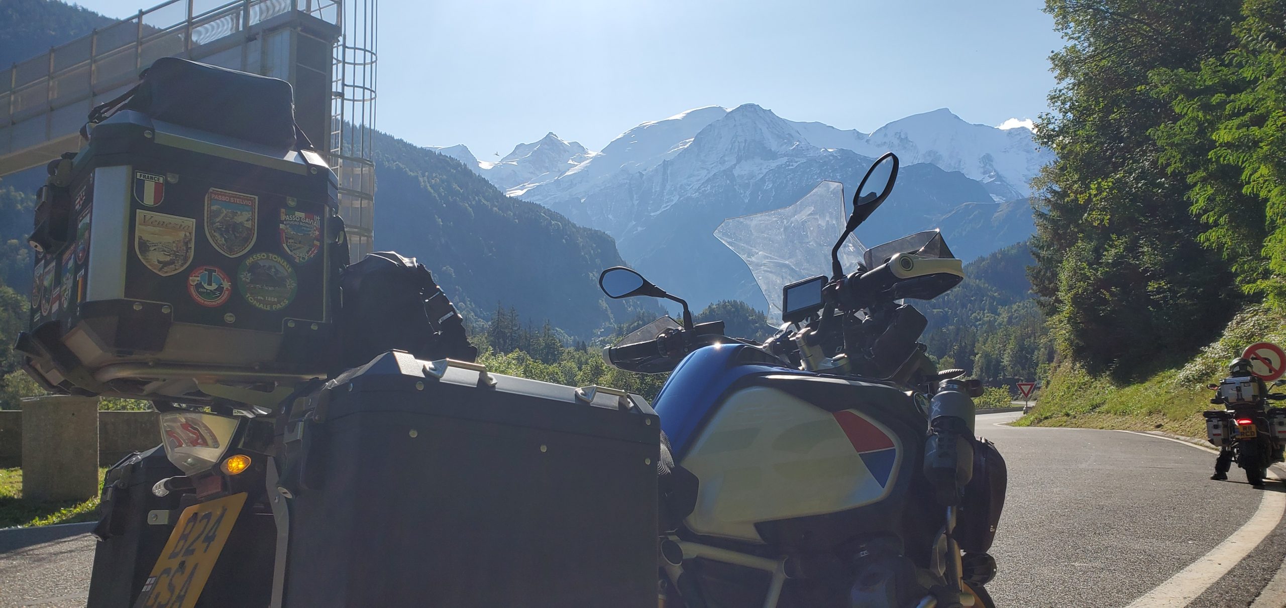Adventure touring motorcycle parked on scenic mountain road with snow-capped peaks in the background