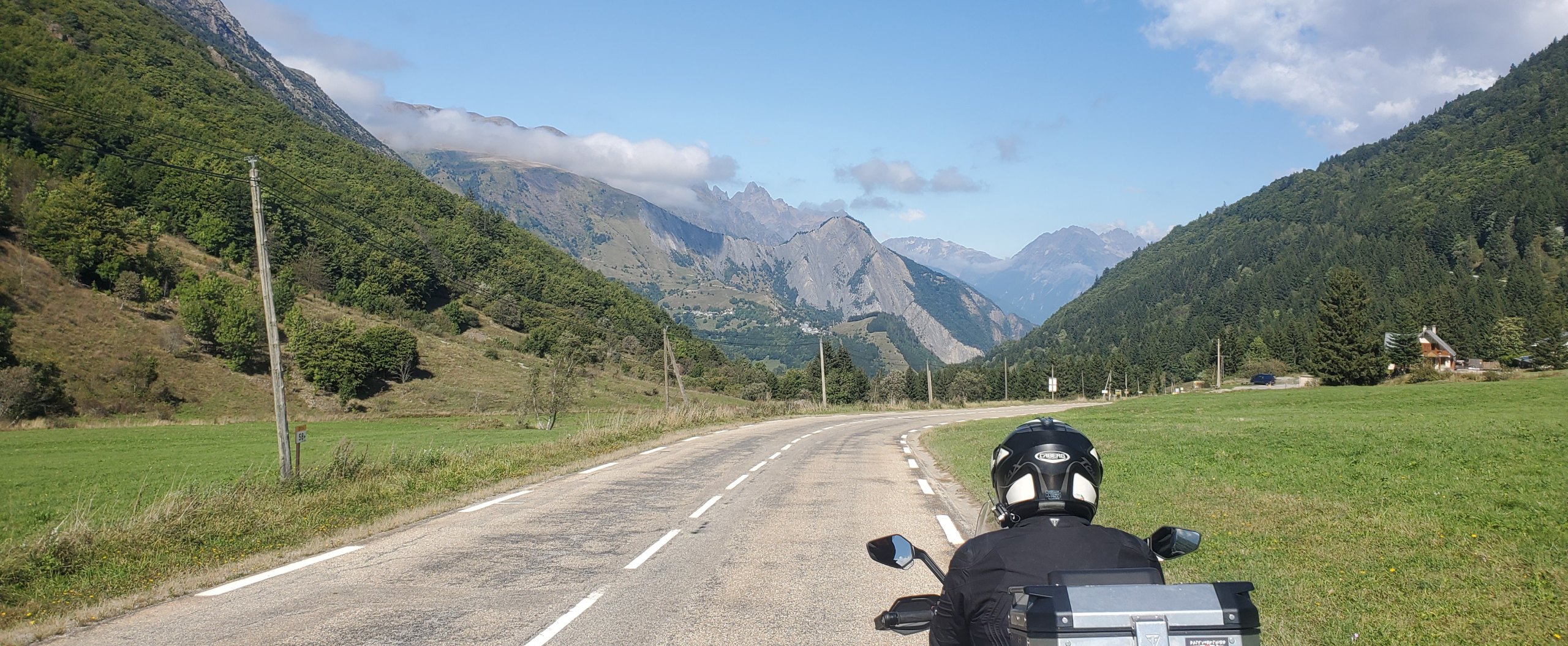 Motorcyclist riding along a scenic road through the French Alps with Mont Blanc in the distance on the legendary Route des Grandes Alpes