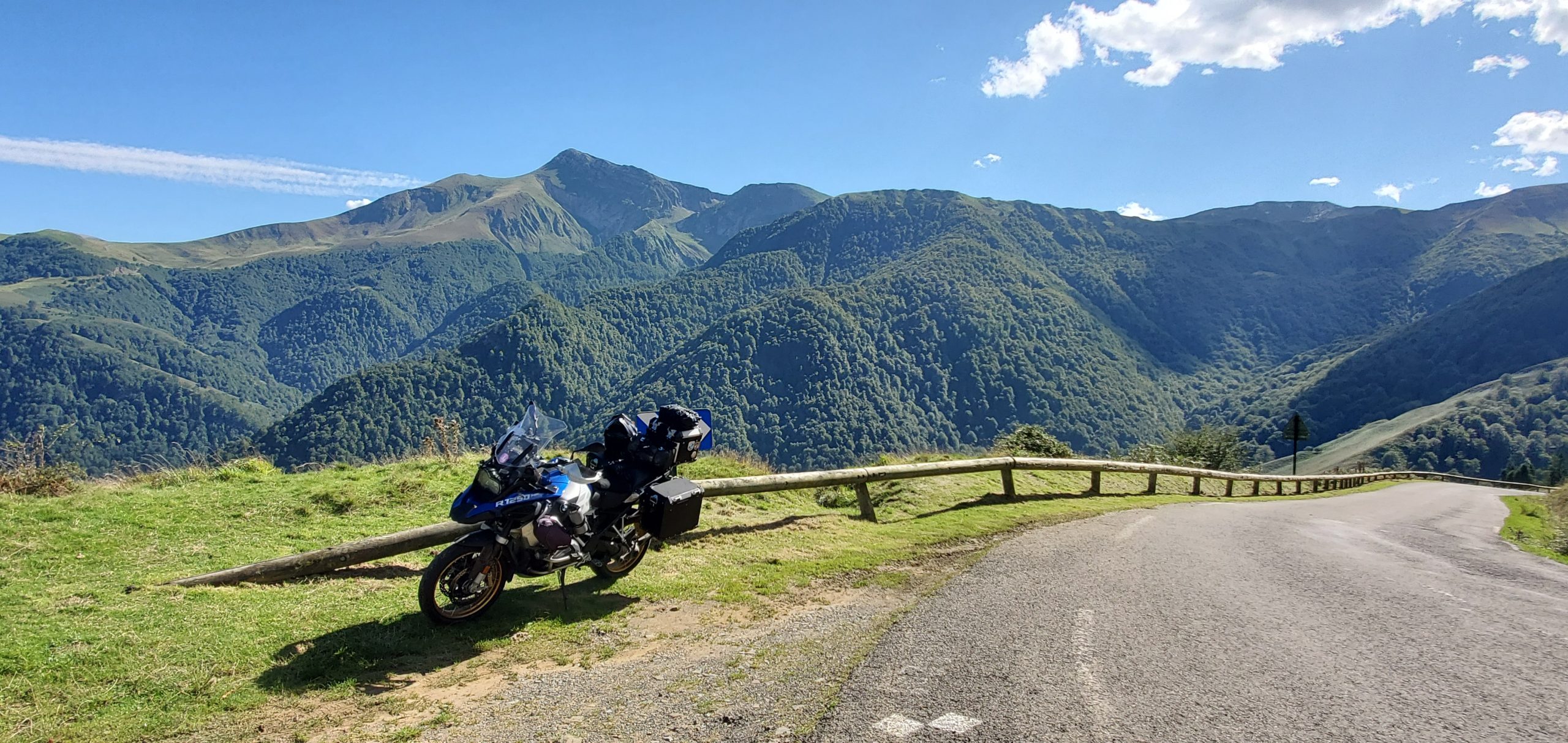 Motorcycle parked along Route Napoléon with stunning alpine mountain views and winding roads under a clear blue sky.