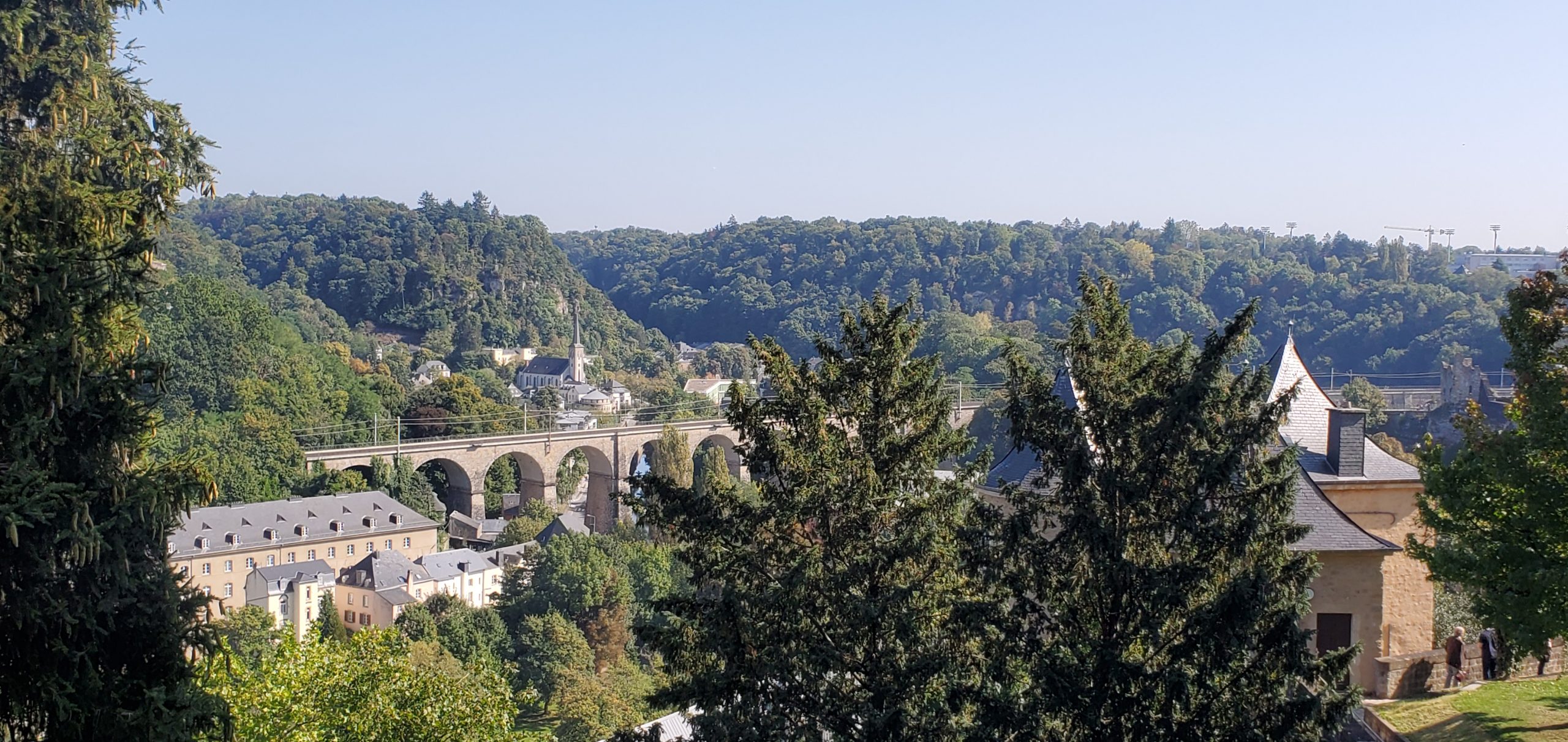 Scenic view of a historic stone viaduct and forested hills in Luxembourg, showcasing hidden roads perfect for motorcycle exploration