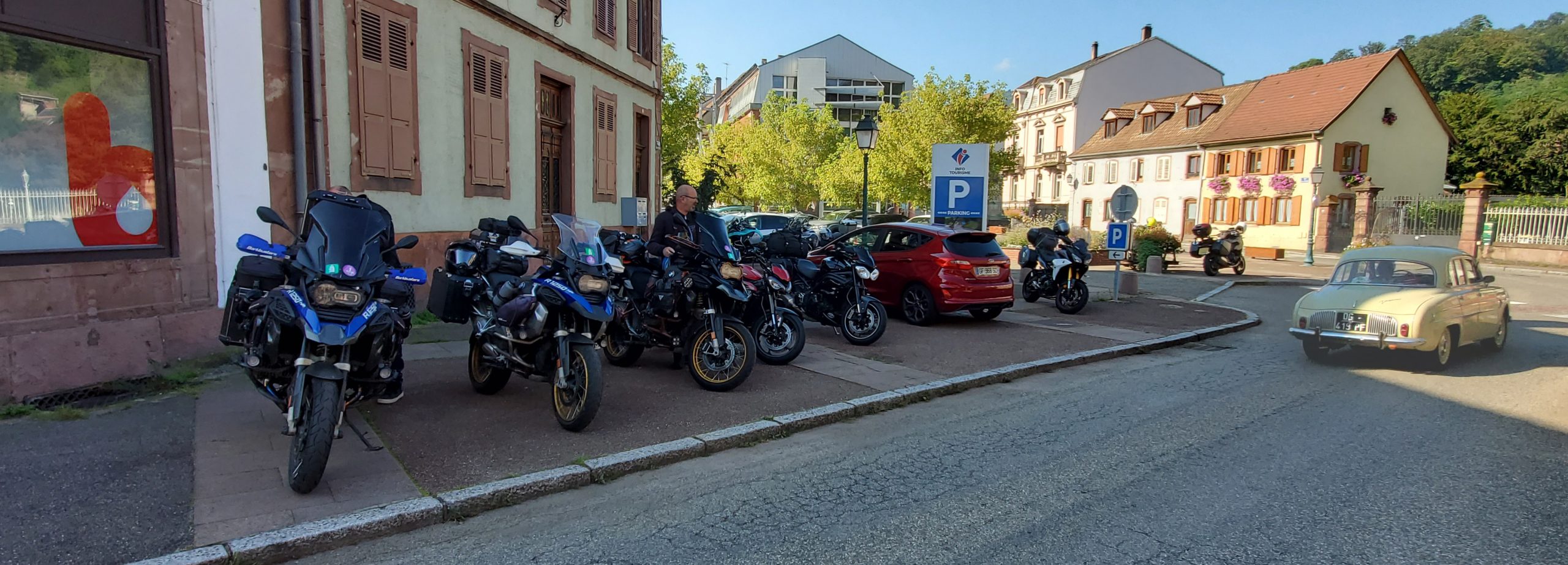 Motorcycles parked outside a French biker-friendly café with riders enjoying a sunny break in a picturesque village
