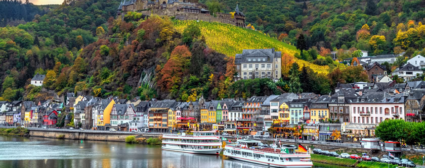 Scenic view of Cochem along the Moselle River, with vineyards, historic buildings, and the river winding through the valley