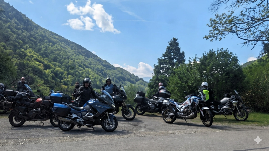 Eurobiketours riders take a break on their motorcycles in a paved scenic overlook, surrounded by the lush green slopes of the Vosges Mountains under a partly cloudy sky.